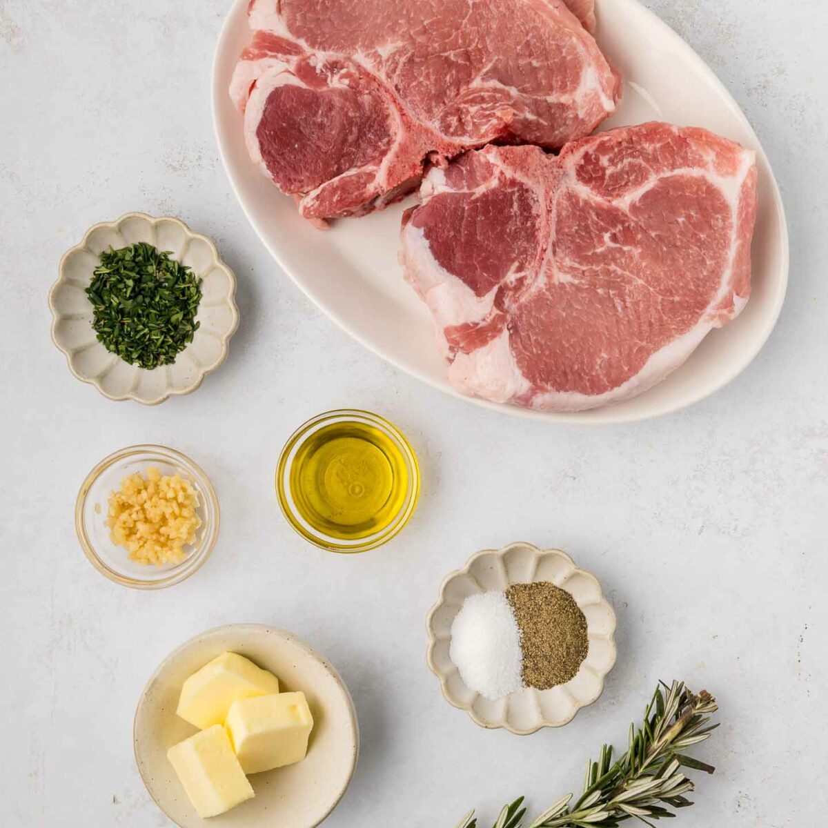 uncooked pork chops on a white plate and rest of ingredients in small bowls