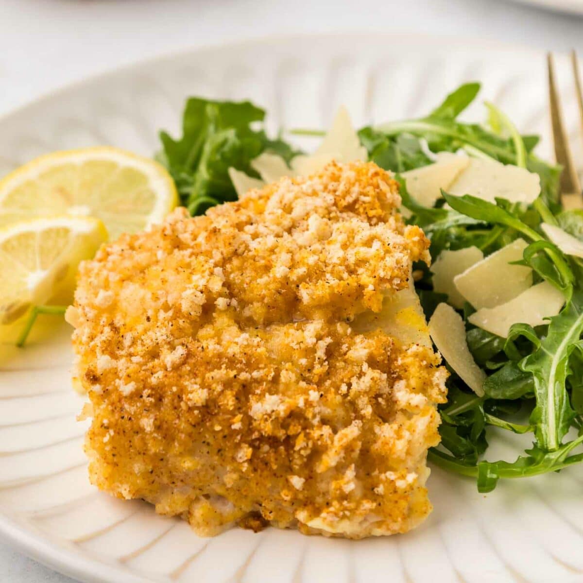 cod plate with a green salad and lemon slices