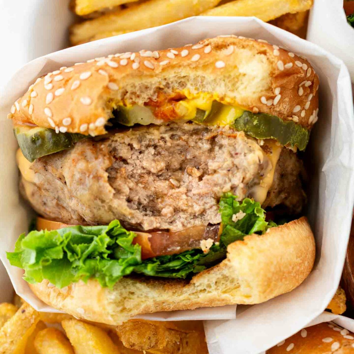 turkey burger with a bite taken out in a casserole dish with fries