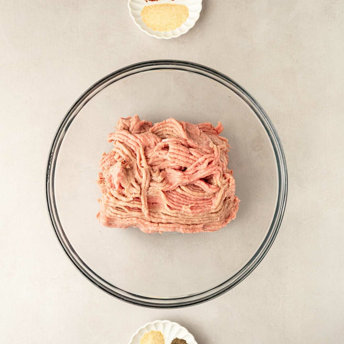 ground turkey in a glass bowl with seasonings in small dishes
