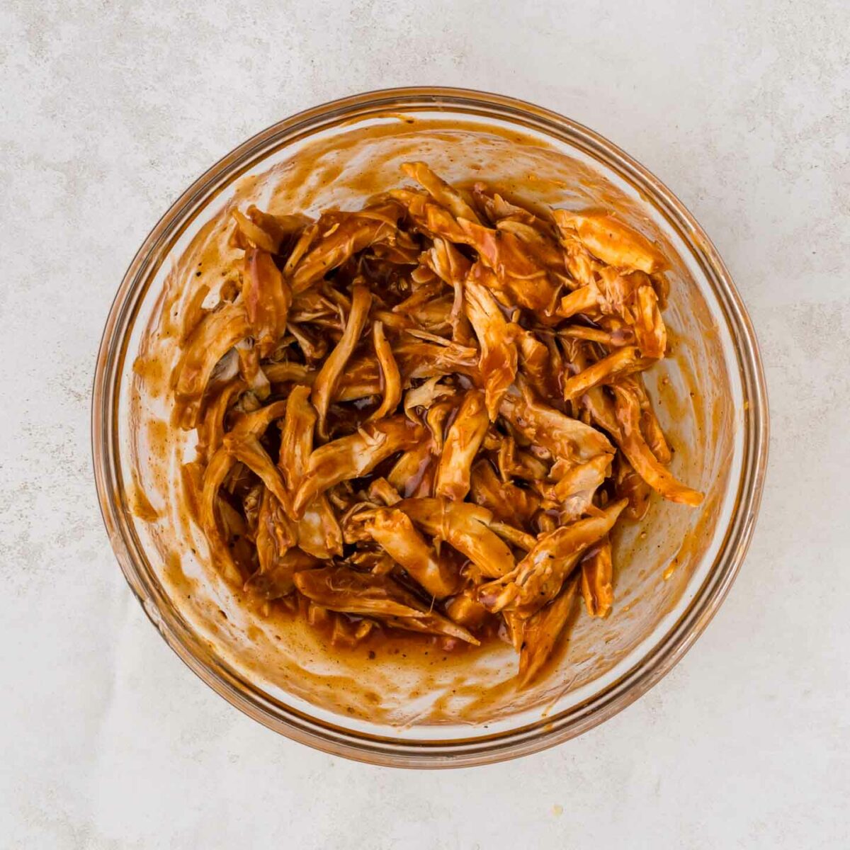 chicken mixed with bbq sauce in a clear bowl