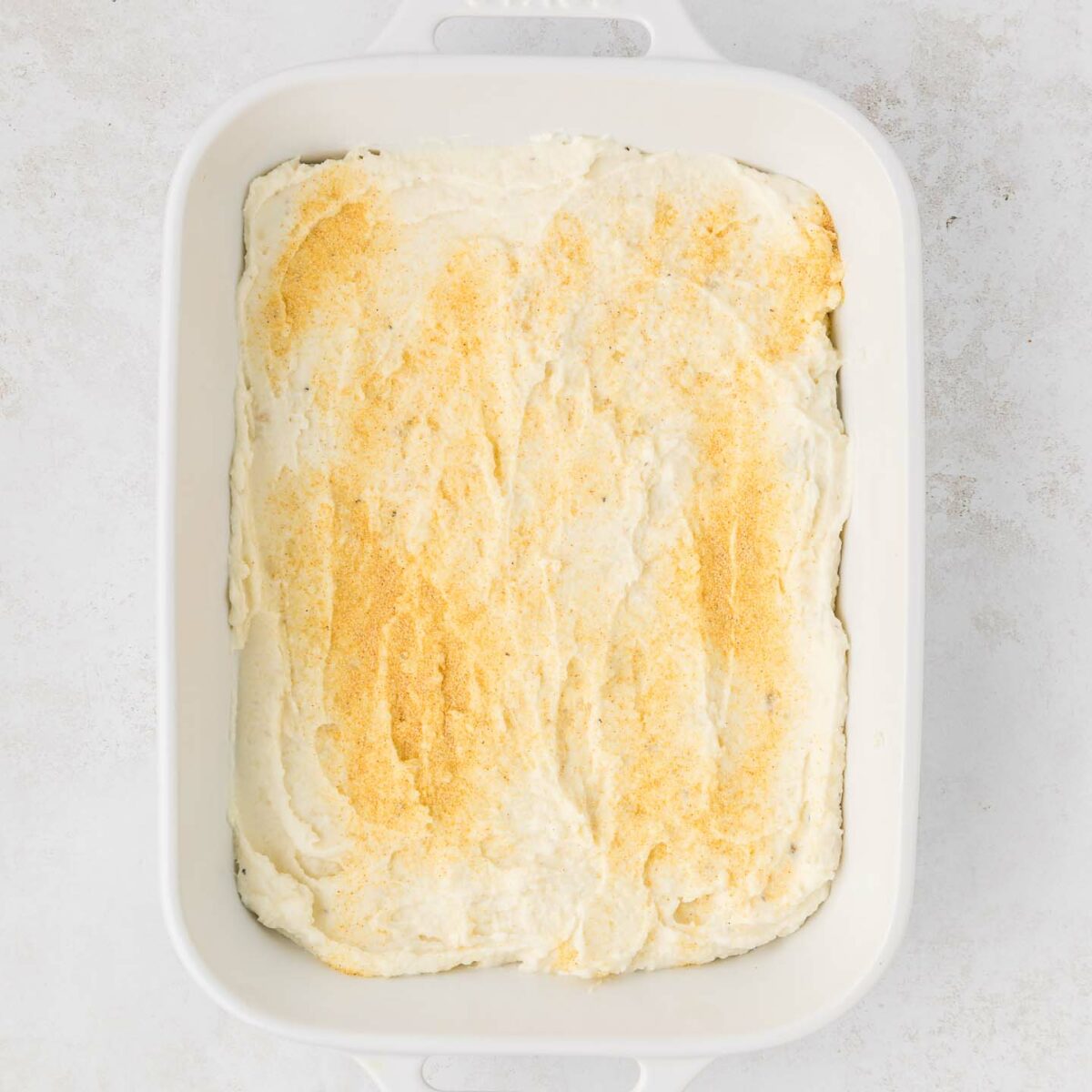 mashed potatoes with seasonings on the bottom of a white dish