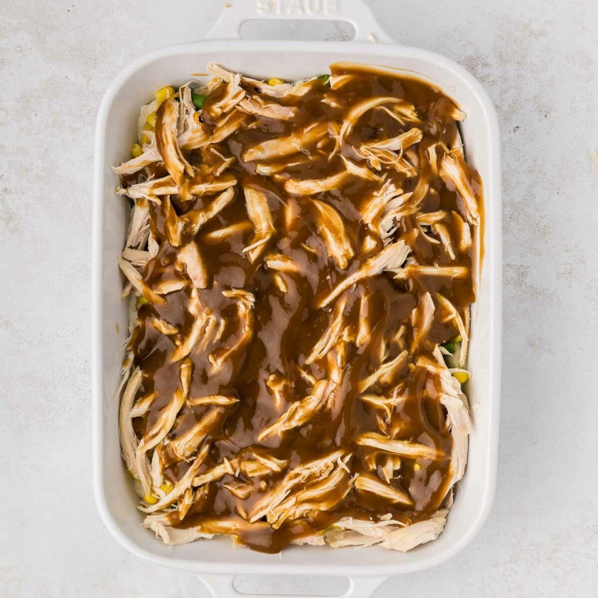 brown gravy poured over chicken in a white dish