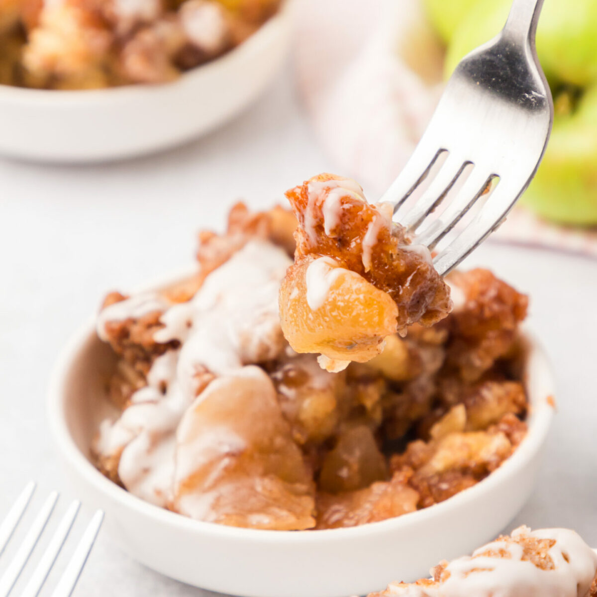 apple cinnamon roll bake on a white plate with a fork showing a bite