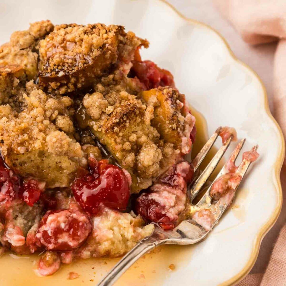 close-up of french toast casserole on a white plate with syrup and a fork