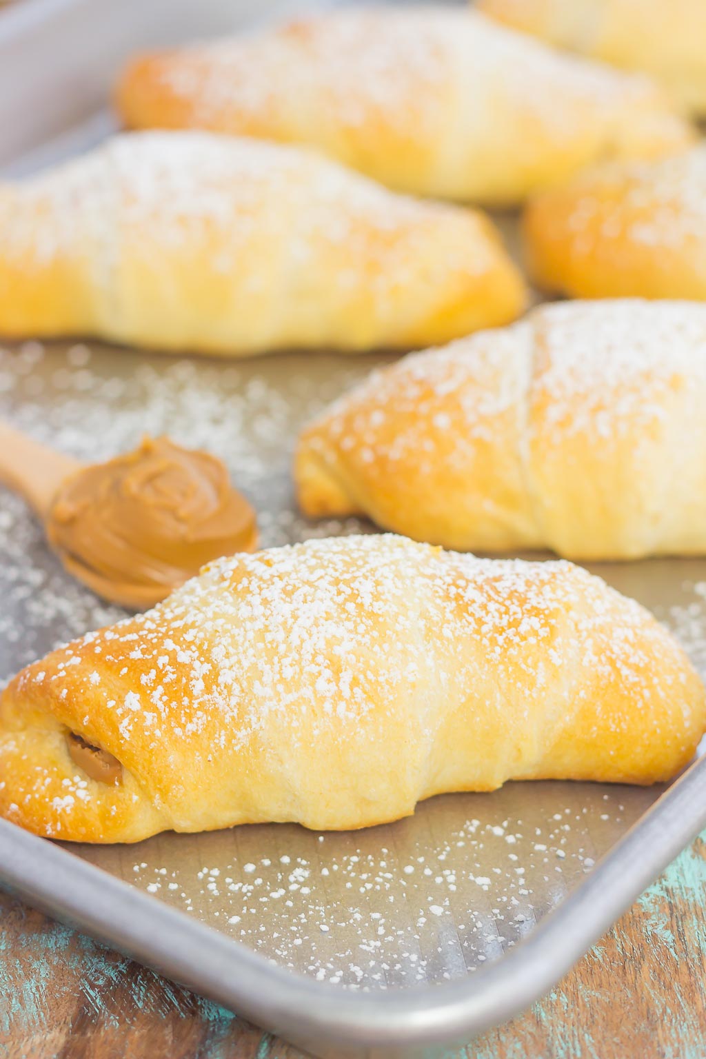 crescent rolls sprinkled with powdered sugar on a silver baking pan