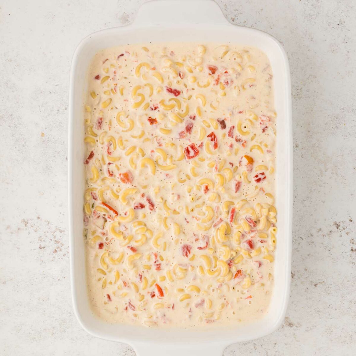 cheese mixture and noodles mixed together and shown in white baking dish