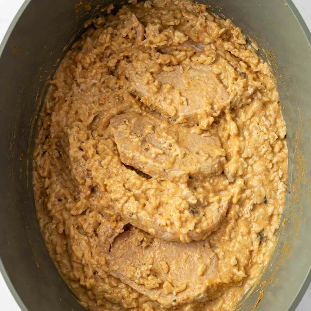 rice cooked and stirred in slow cooker with pork chops on top
