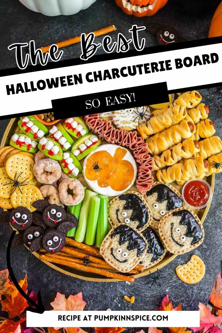A Halloween charcuterie board with themed snacks: cookies decorated as monsters and vampires, wrapped hot dogs resembling mummies, cheese, crackers, celery sticks, donuts, and dips, all arranged festively with plastic spiders.