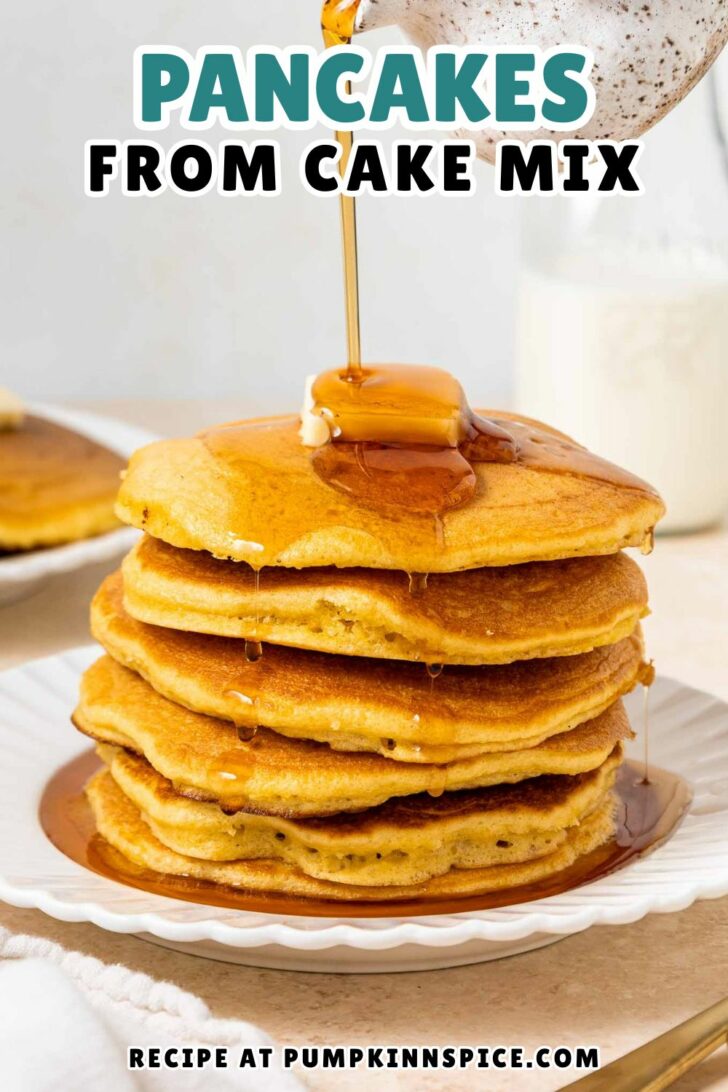A stack of golden pancakes topped with butter is being drizzled with syrup on a white plate. Text reads: “PANCAKES FROM CAKE MIX. Recipe at pumpkinnspice.com.” A glass of milk and more pancakes are in the background.