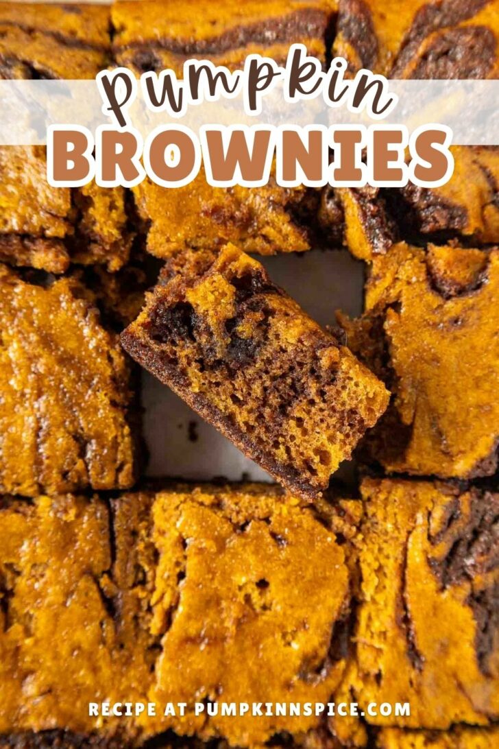 Top-down view of pumpkin brownies, with one square lifted to show its marbled pumpkin and chocolate texture. Text over the image reads Pumpkin Brownies and Recipe at pumpkininspice.com.
