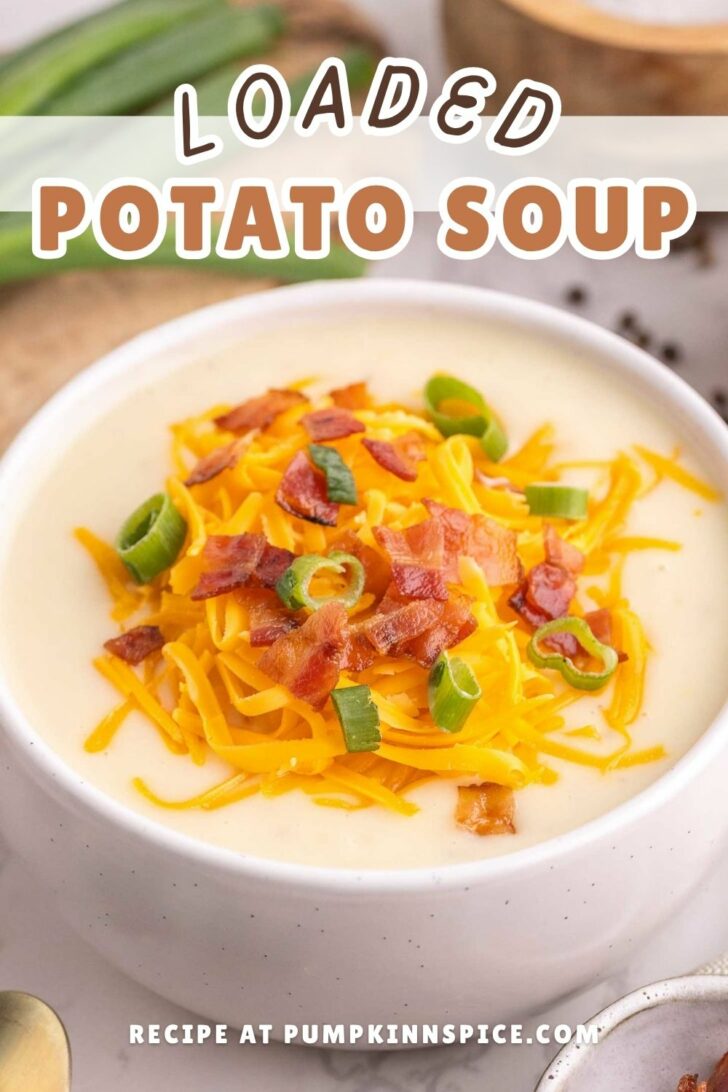 A bowl of creamy potato soup topped with shredded cheddar cheese, crispy bacon pieces, and sliced green onions. Text reads Loaded Potato Soup and Recipe at pumpkininspice.com.