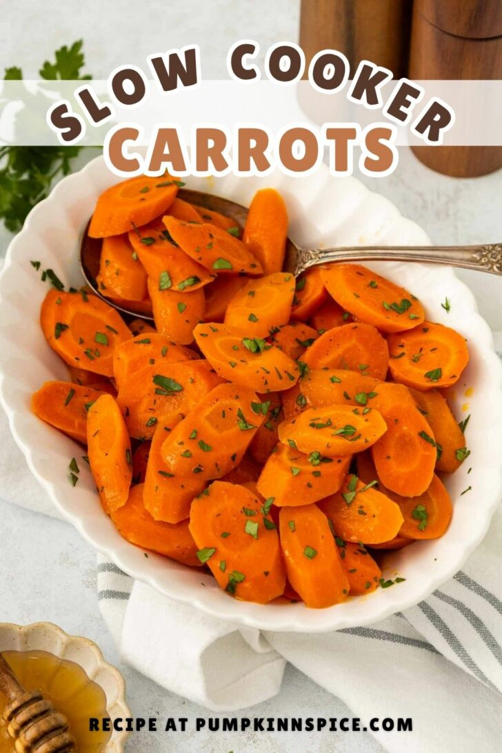 A white bowl filled with sliced cooked carrots garnished with chopped herbs. A silver spoon rests in the bowl, and the text Slow Cooker Carrots appears above. The edge shows Recipe at pumpkinnspice.com.