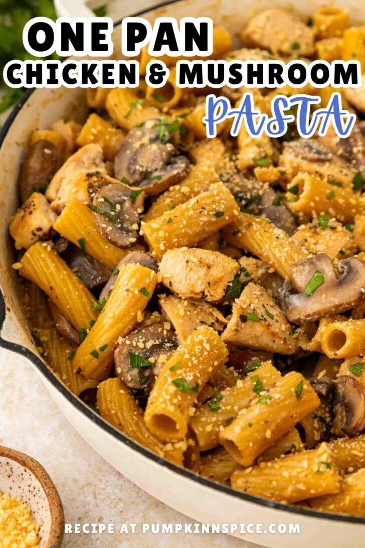 A close-up of a skillet filled with rigatoni pasta, chicken pieces, mushrooms, and a creamy sauce, garnished with parsley and grated cheese. Text reads: One Pan Chicken & Mushroom Pasta. Recipe at pumpkininspice.com.