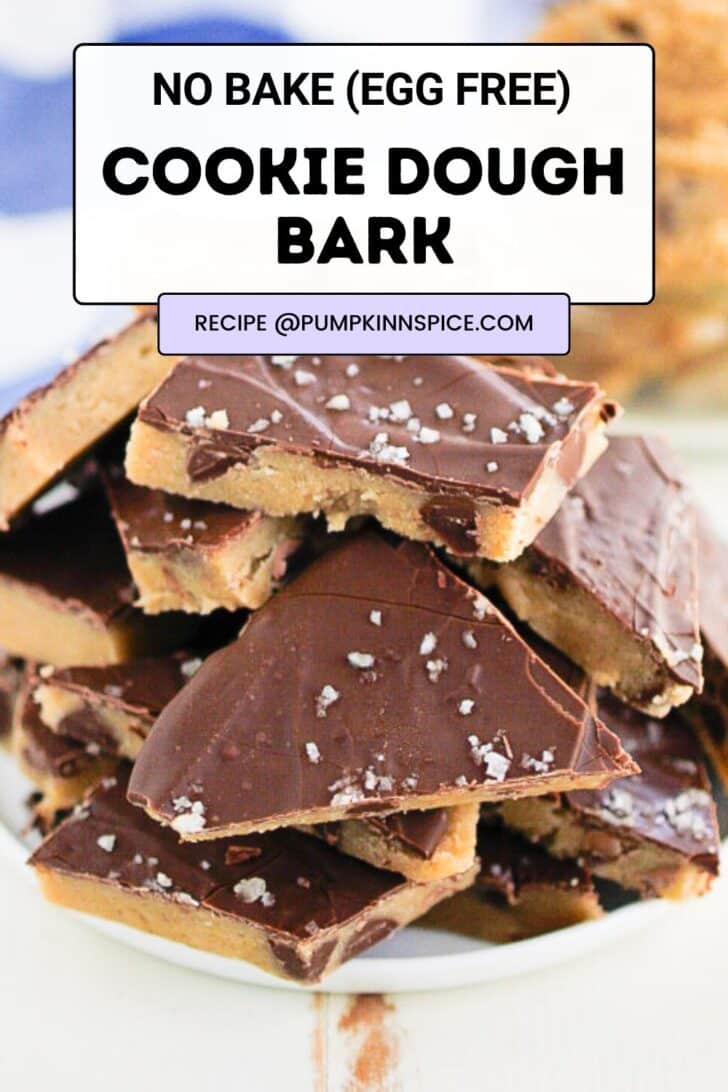A plate stacked with pieces of cookie dough bark topped with chocolate and sea salt. Text on the image reads: No Bake (Egg Free) Cookie Dough Bark. Recipe @pumpkinnspice.com.