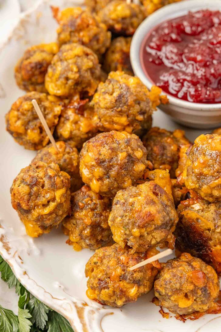 A plate of stuffing balls with toothpicks, served next to a bowl of cranberry sauce.